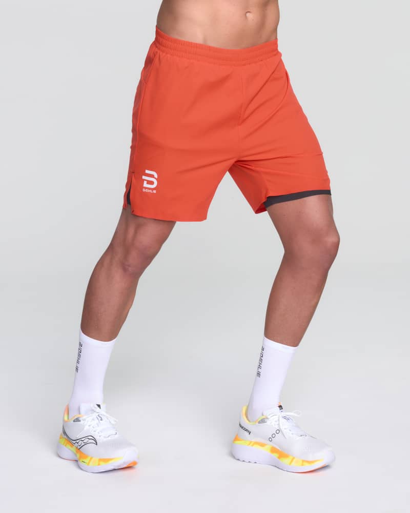 Male runner wearing Dæhlie's red Shorts Run 365, showcasing the side split and active fit for running.