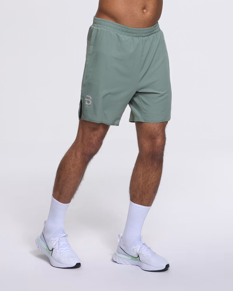 Runner's front side view in Dæhlie's green Shorts Run 365, showing the 7.5-inch inseam.