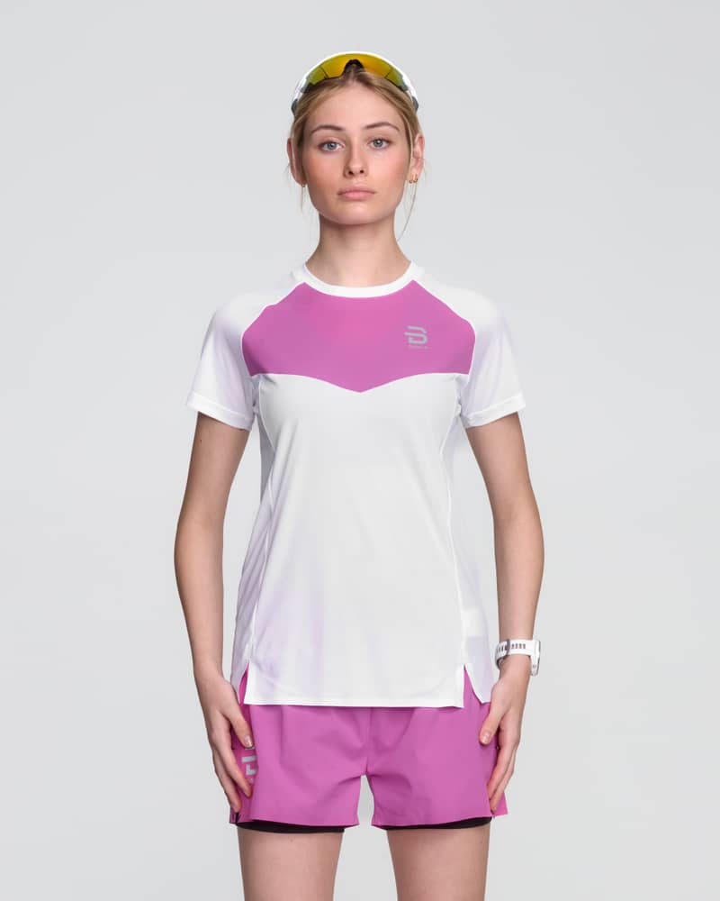 Woman in a white Dæhlie Run 365 t-shirt with pink color blocking, showing a comfortable and stylish running fit.