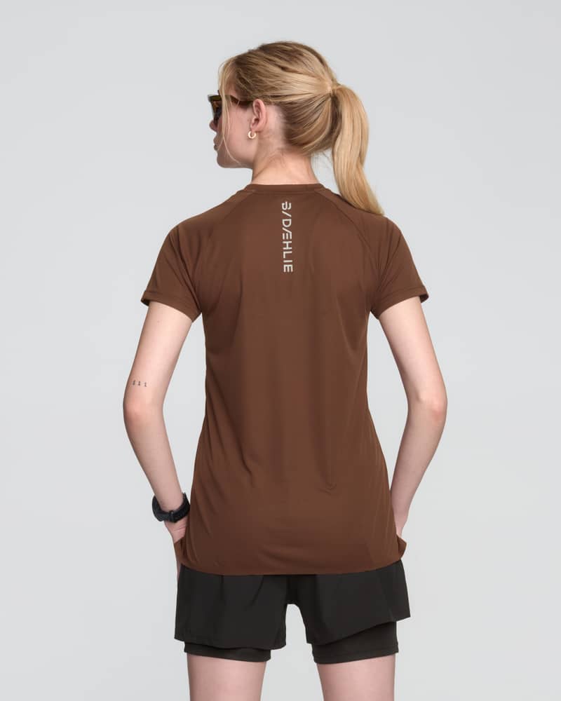 Rear view of a woman in the brown Dæhlie Run 365 t-shirt, emphasizing its moisture-wicking properties.
