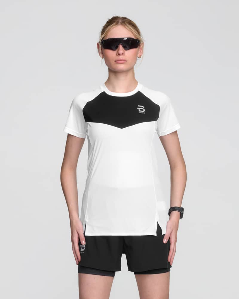 Female runner in a white Dæhlie Run 365 t-shirt with black color blocking, designed for high-performance workouts.