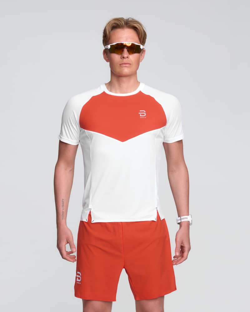 Runner in a white Dæhlie Run 365 t-shirt for men with red chest panel, designed for optimal movement.