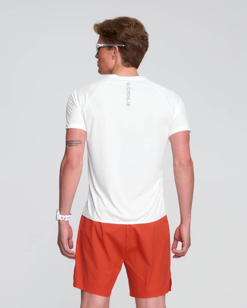 Rear view of a man wearing the white and red Dæhlie Run 365 t-shirt, showing off the breathable fabric.