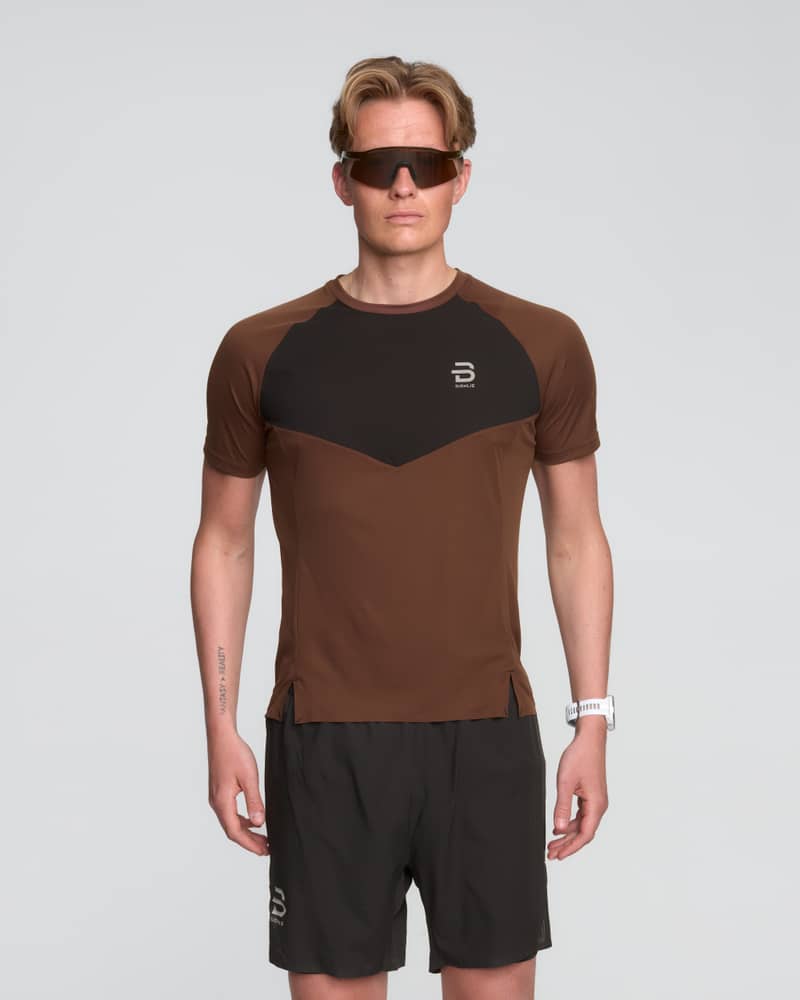 Male runner in a brown Dæhlie Run 365 t-shirt with black details, ideal for both training and race day.