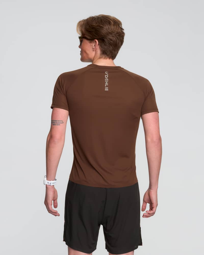 Back shot of a runner in the brown Dæhlie Run 365 t-shirt for men, highlighting its athletic fit.