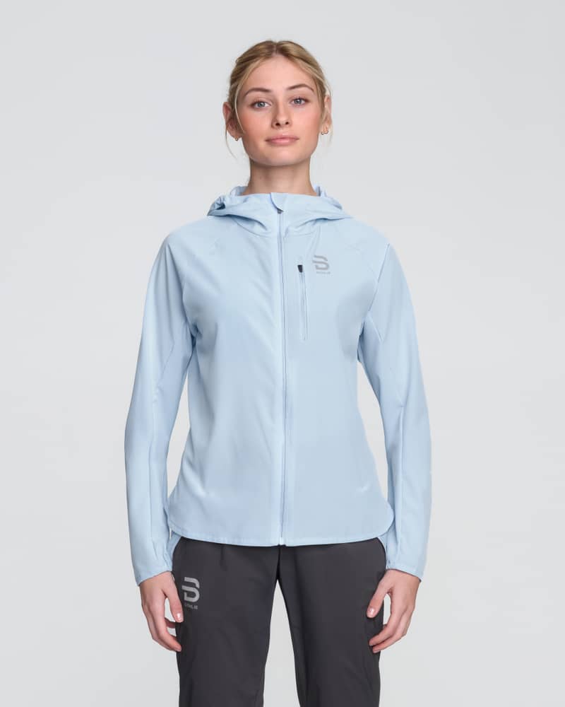 Woman wearing Dæhlie's light sky blue Jacket Run 2.0, a lightweight and breathable running jacket.