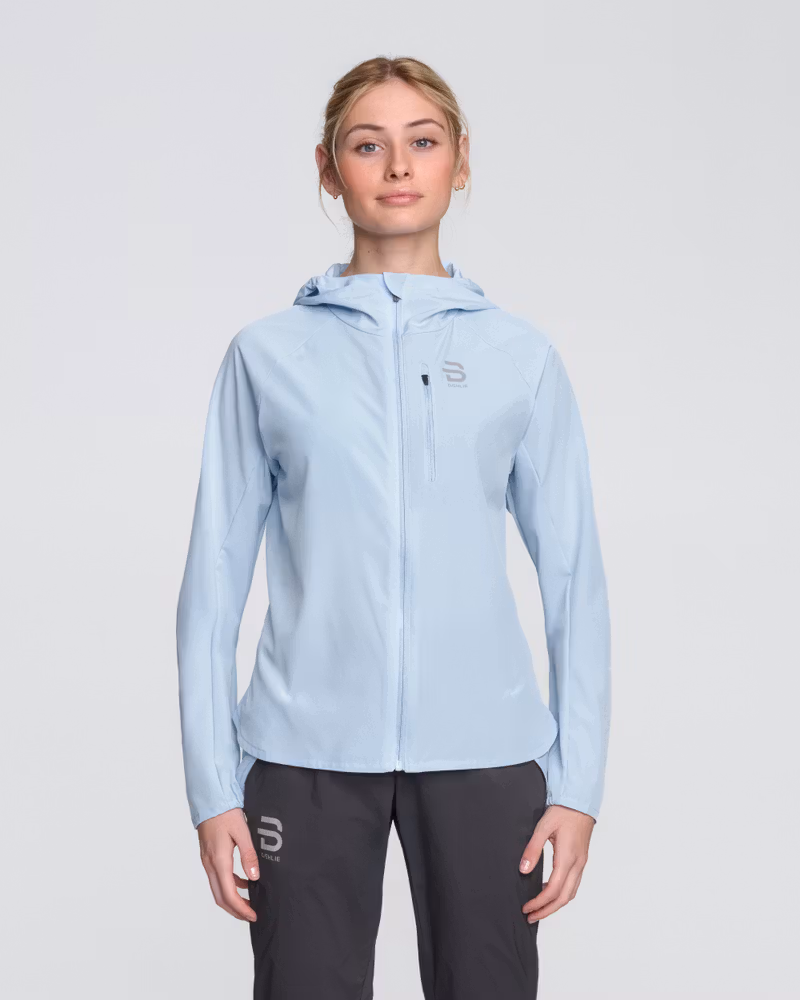 Woman wearing Dæhlie's light sky blue Jacket Run 2.0, a lightweight and breathable running jacket.