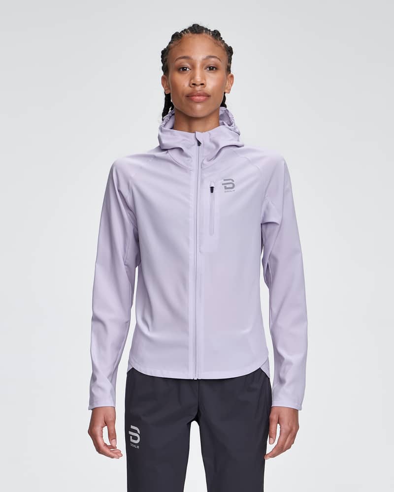 Woman in a lavender Dæhlie Jacket Run 2.0, a lightweight running jacket with a regular fit and fixed hood.