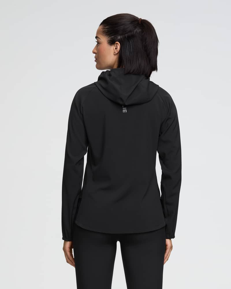 Back of a female model wearing the black Dæhlie Jacket Run 2.0 with a fixed hood for weather protection.