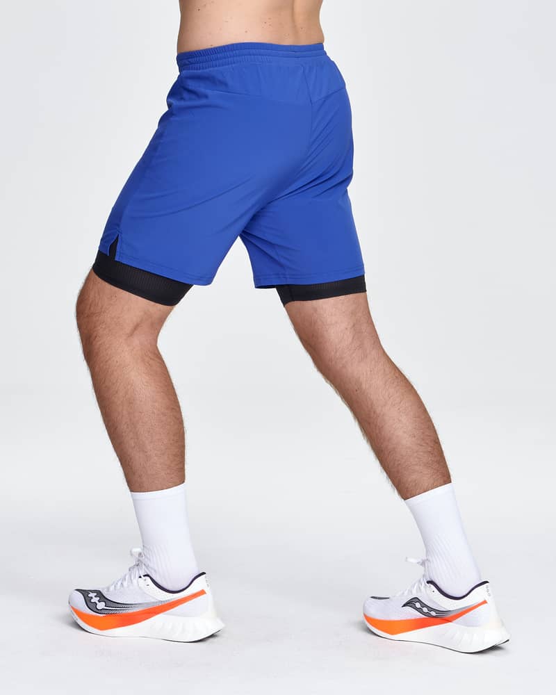 Back side view of a runner wearing Dæhlie's bright blue shorts, showing the active 6-inch inseam fit.