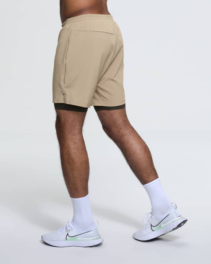 Back view of a man running in Dæhlie's tan 2-in-1 shorts, showcasing the 6-inch inseam length.