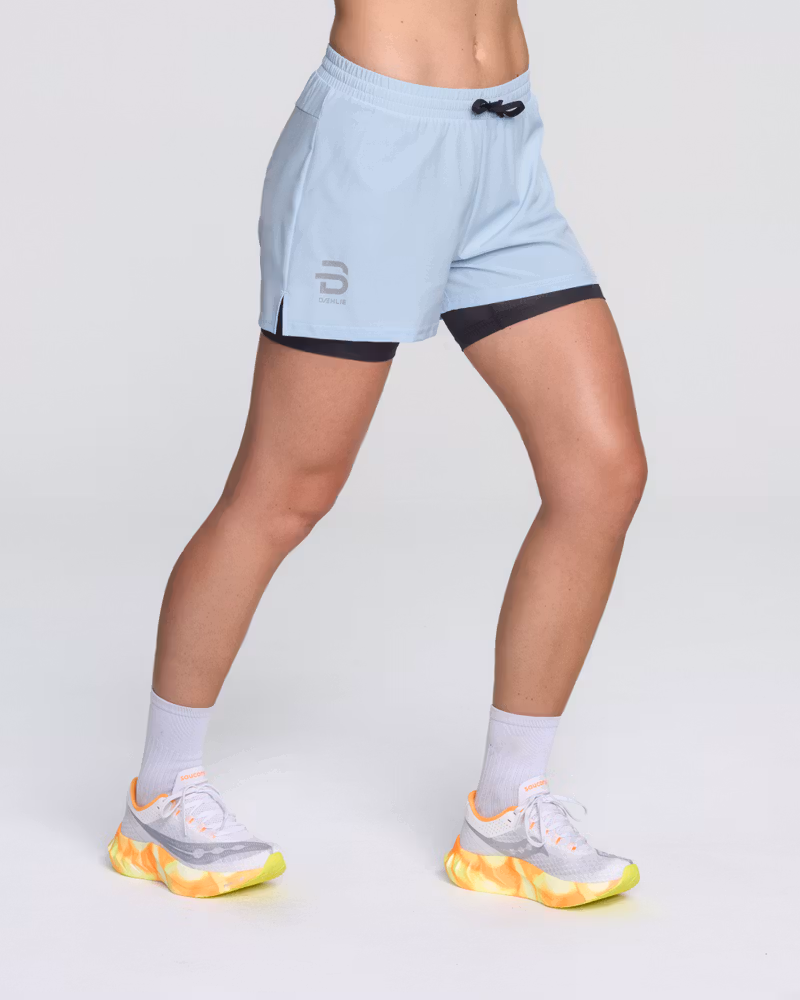 Runner's front side view in Dæhlie's light blue Shorts Run 2 in 1 with a supportive inner tights.