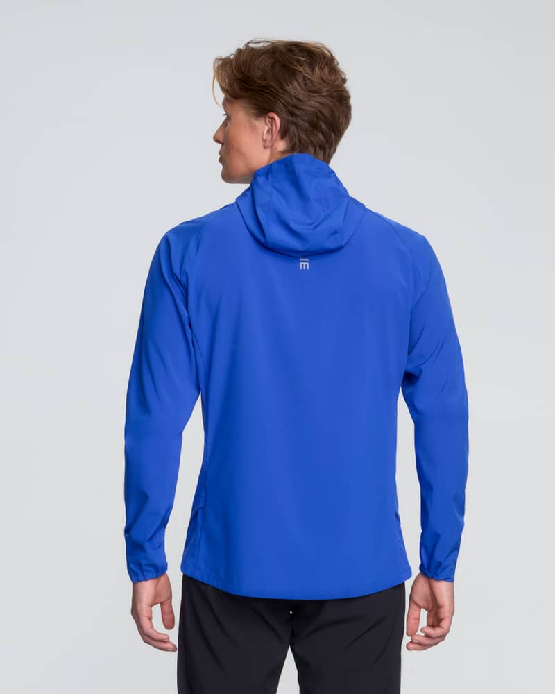 Back of runner wearing the blue Dæhlie Jacket Run 2.0, a breathable jacket ideal for daily runs.