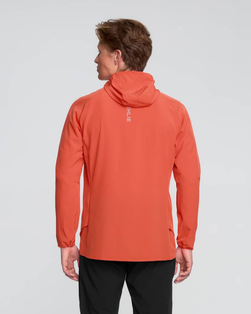 Back view of a runner wearing the red Dæhlie Jacket Run 2.0, highlighting the split hem for mobility.