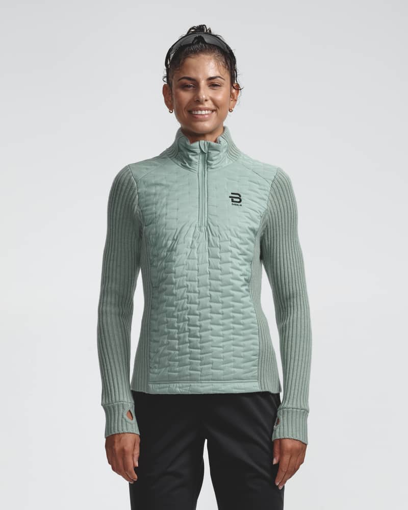 Woman wearing the light green Half Zip Comfy 2.0 women's sweater, showing the wind-resistant quilted front.