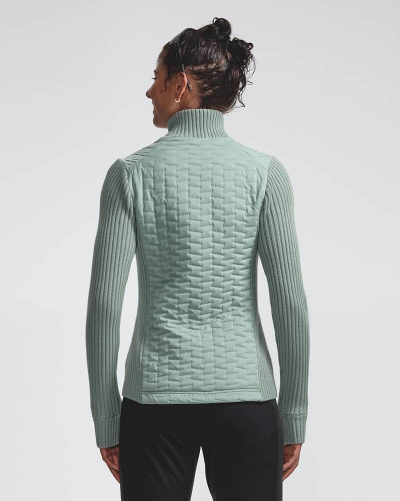 Back view of a woman in the light green Full Zip Comfy jacket, highlighting the full-body ultrasonic quilting.