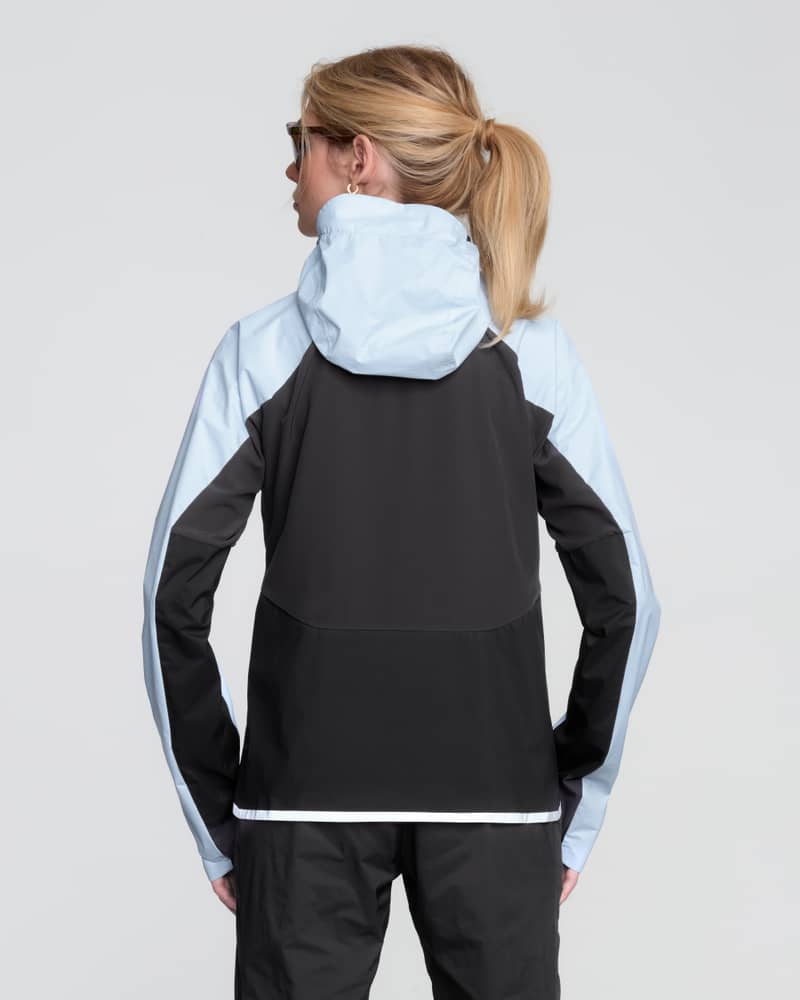 Back view of the women's Dæhlie Advance Light running jacket, showing the light blue hood and shoulders with a black flexible lower panel.