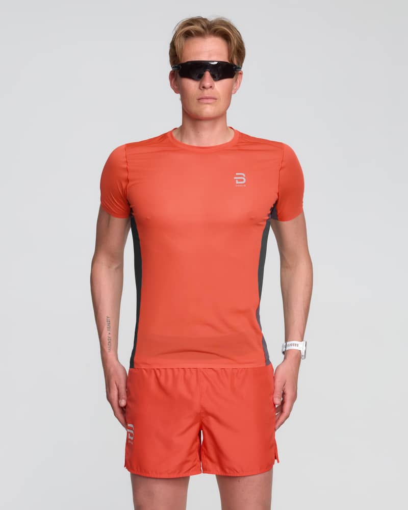 Male runner in the vibrant red Dæhlie T-Shirt Air, showcasing its athletic fit for high-intensity training sessions.