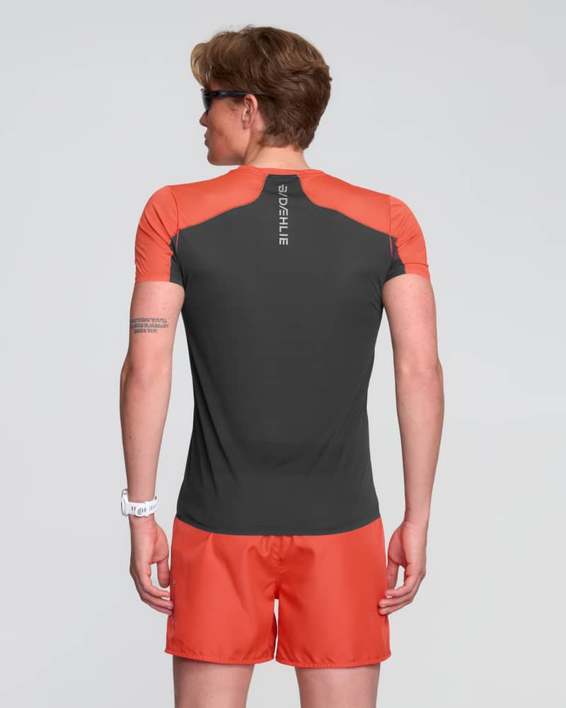 Back of a male runner wearing the red Dæhlie T-Shirt Air, emphasizing the moisture-wicking technology for staying cool.