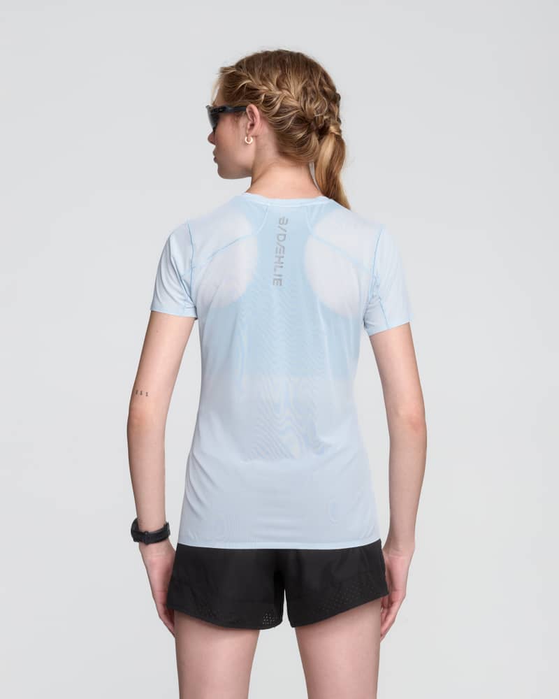 Back of a female runner in the light blue Dæhlie T-Shirt Air, showcasing the moisture-wicking back panel for warm runs.