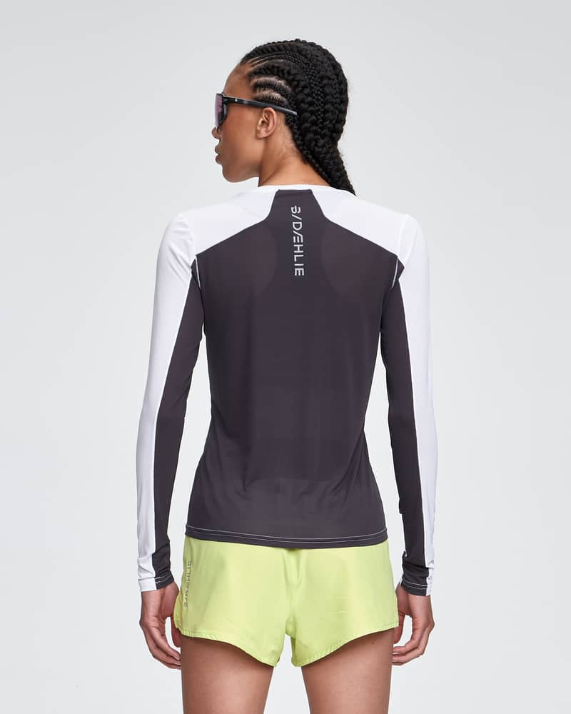 Back view of the woman in the white and black Dæhlie Long Sleeve Air, showcasing the high-performance, breathable design.