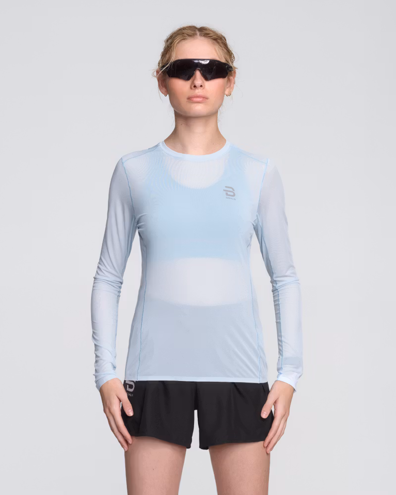 Woman wearing the light blue Dæhlie Long Sleeve Air, a technical running shirt with moisture-wicking fabric.