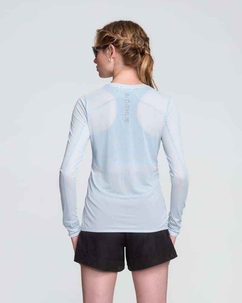 Back view of a woman in the light blue Dæhlie Long Sleeve Air, showing the breathable panels for high-output training.