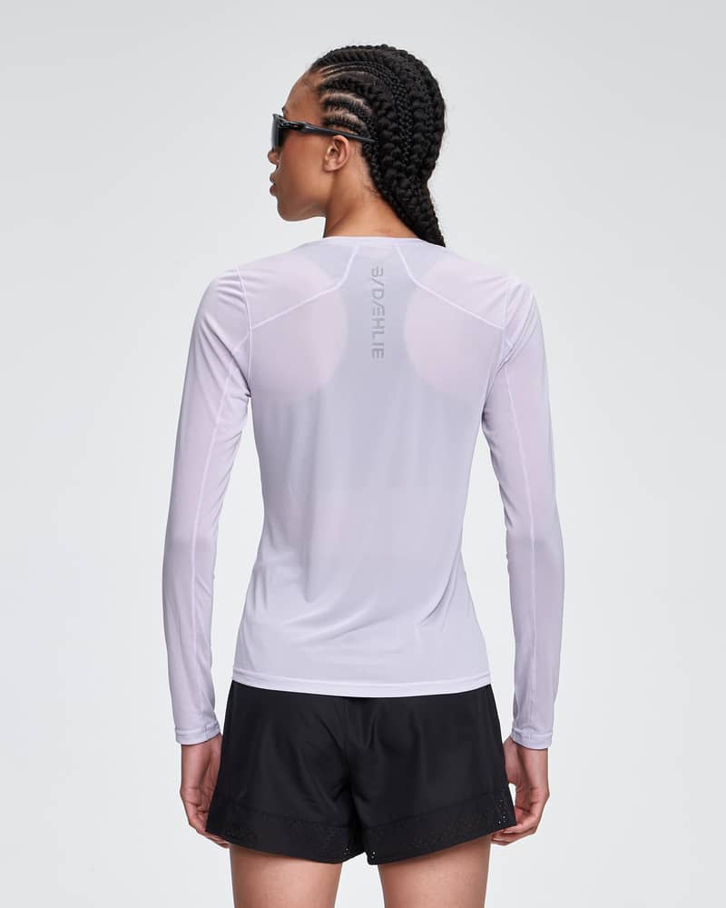 Back view of a woman in the light purple Dæhlie Long Sleeve Air, highlighting the shirt's athletic regular fit.