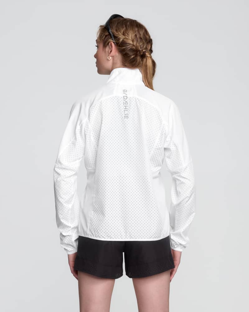 Back of a woman in the white Dæhlie Jacket Air, showing the active fit for unrestricted movement while running.