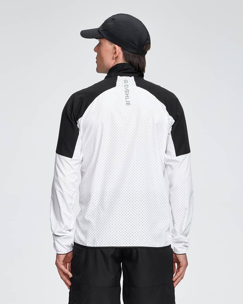 Rear view of a male runner in the white and black Dæhlie Jacket Air, showing the raglan sleeves for optimal arm movement.