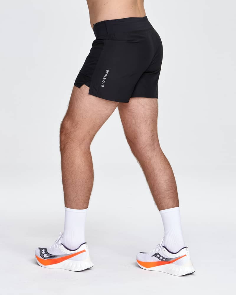 Male model running in Dæhlie's black 5-inch shorts, demonstrating the freedom of movement from the crotch gusset.