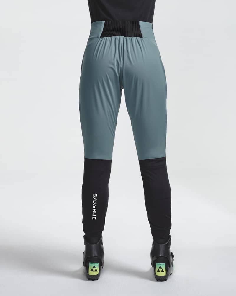 Back view of a woman wearing teal and black Challenge 3.0 ski pants, showing the flattering fit and durable panels.