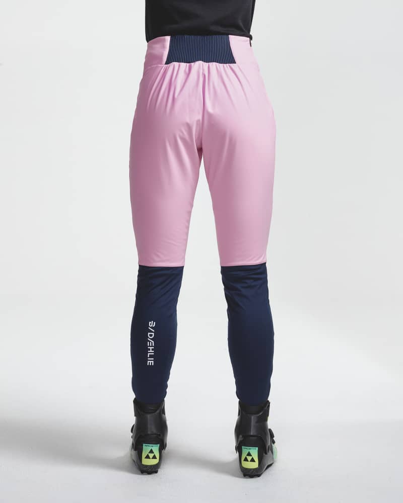 Back view of a woman in pink and navy Challenge 3.0 ski pants, highlighting a comfortable wide waistband.