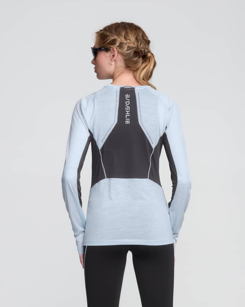 Back of a female runner in a light blue Dæhlie tech wool top, showing the ventilation panel for moisture control.