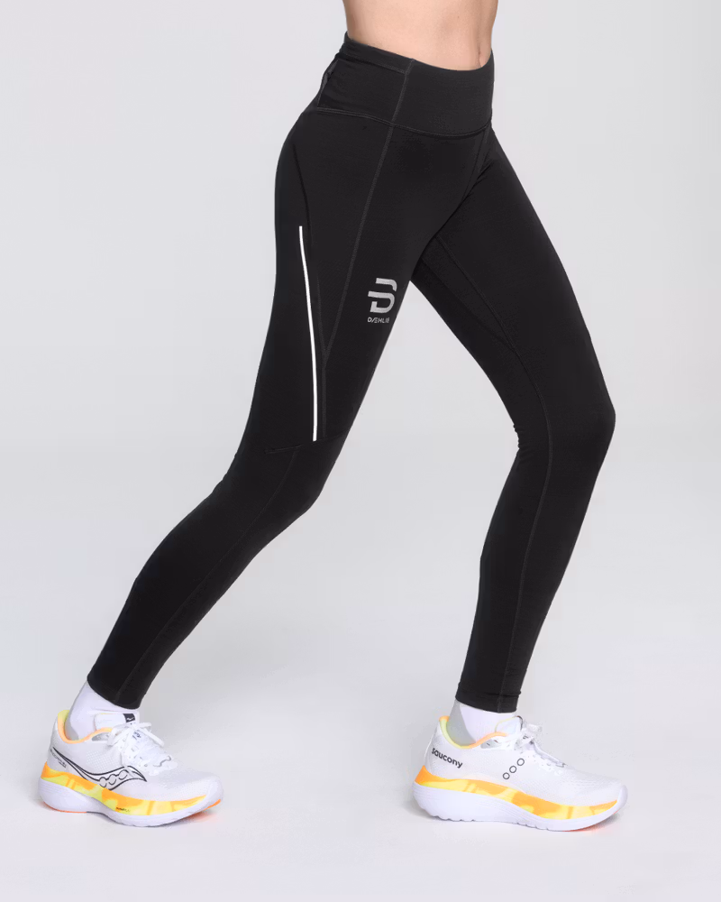 Woman wearing Dæhlie's black Tights Tech Wool, designed with shaped knees and technical fabrics with wool blend for warmth.