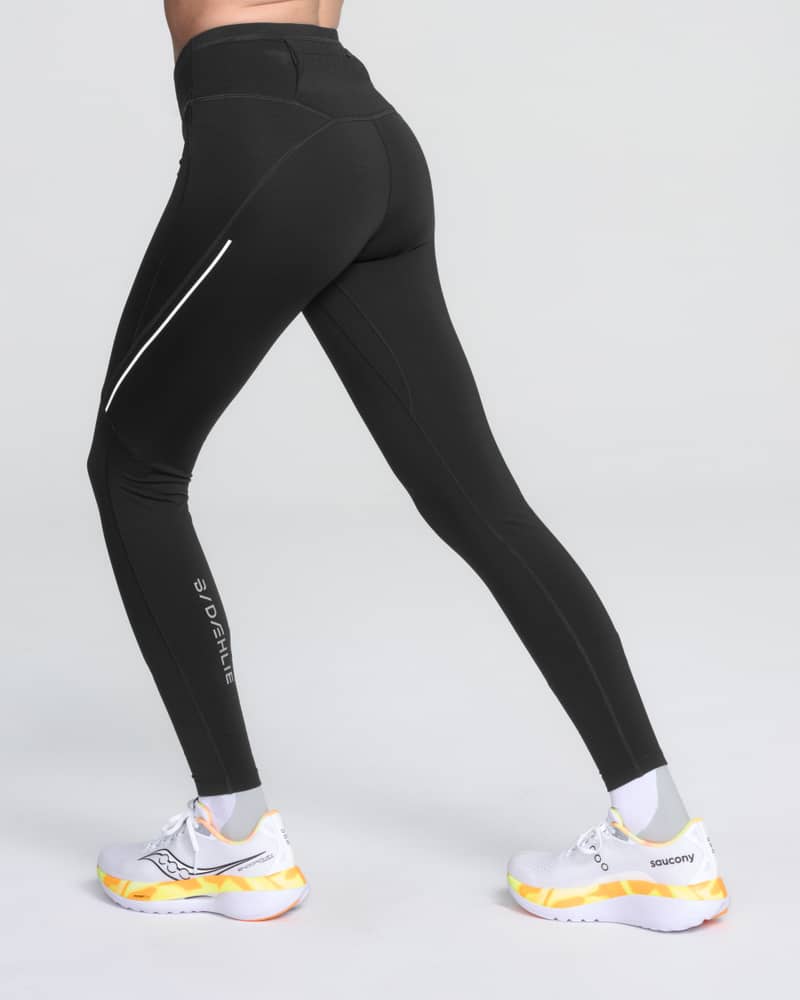 Side view of a female runner showing the Dæhlie Tights Tech Wool with reflective details for running in low-light conditions.