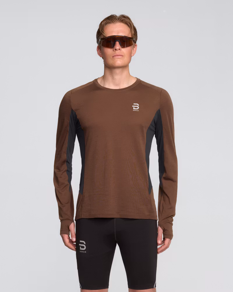 Man wearing the brown and black Dæhlie Long Sleeve Tech Wool, a moisture-wicking merino running top.