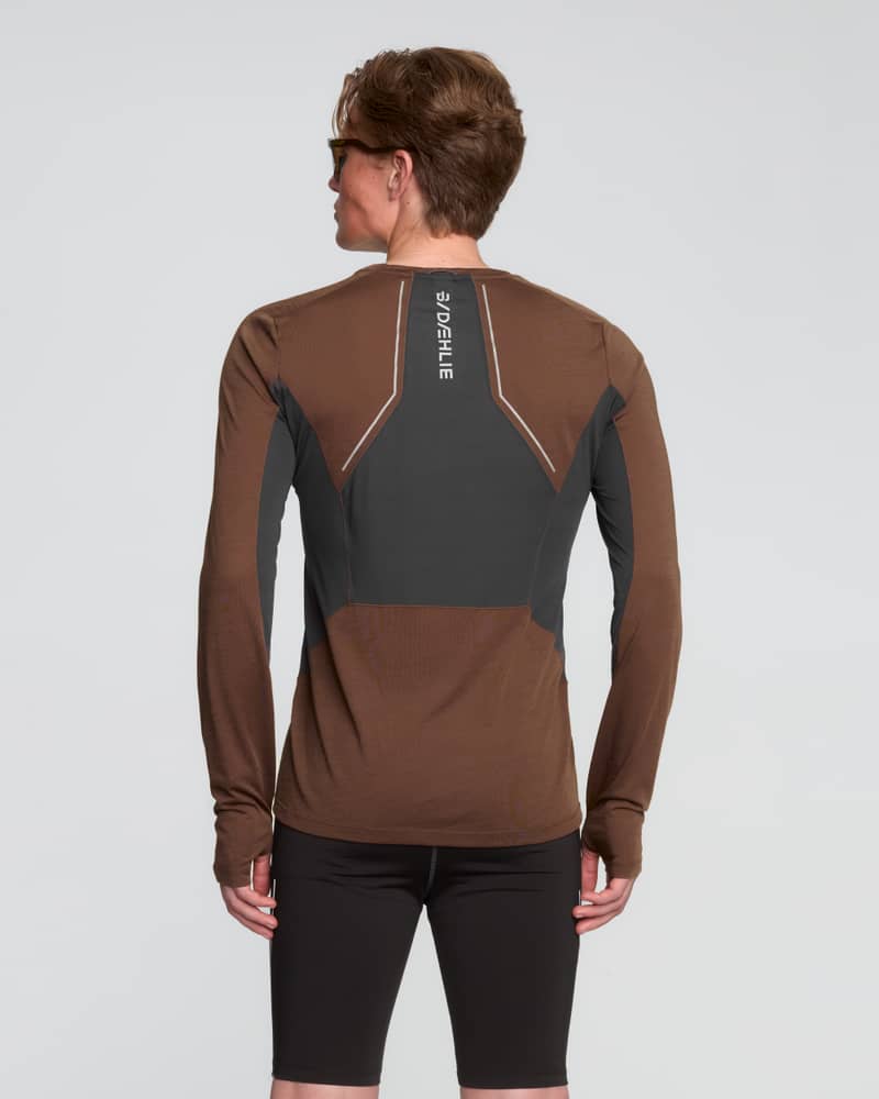 Rear view of a runner in a brown Dæhlie tech wool long sleeve, showing the reflective logo for low-light runs.