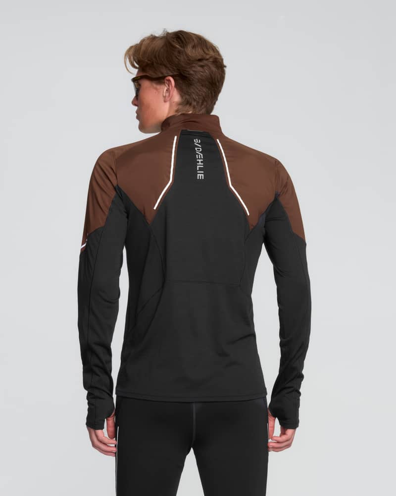 Rear view of a man wearing the brown Dæhlie Half Zip Tech Wool, a technical running midlayer with wool panels.