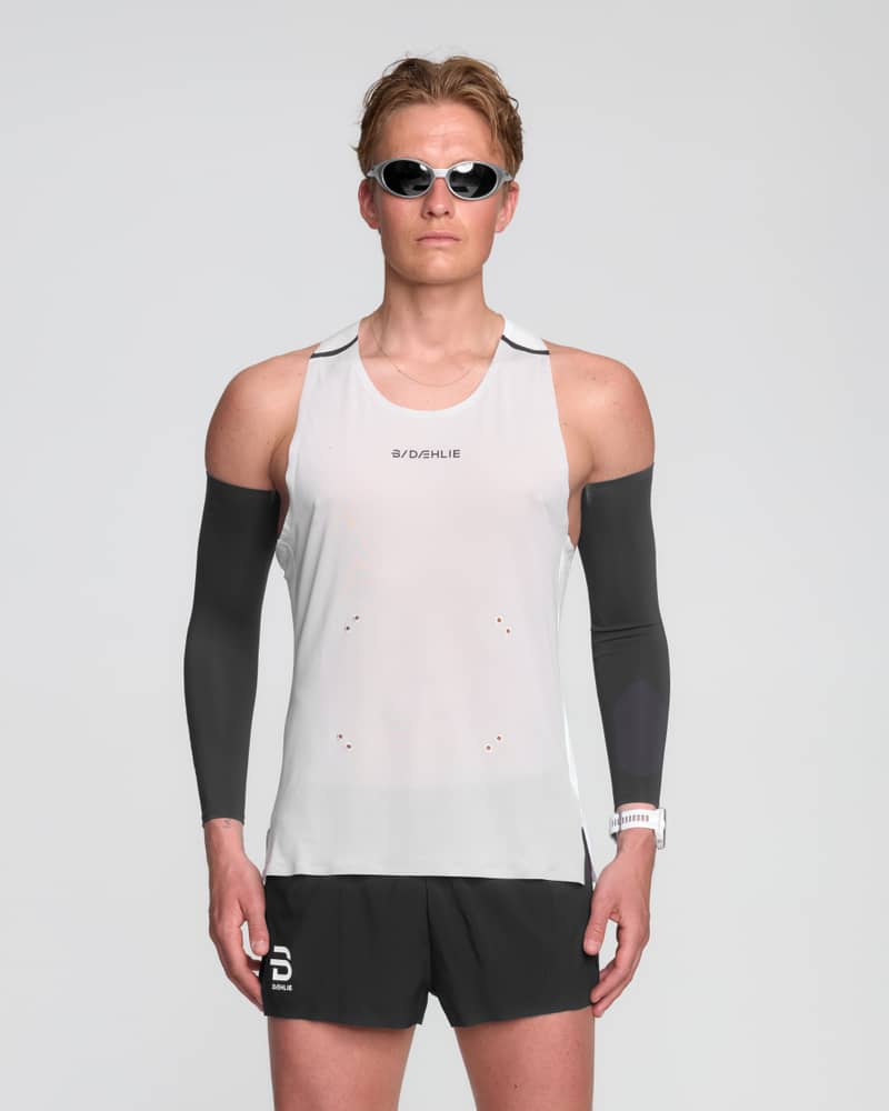 Male runner in a Dæhlie white running singlet with breathable, lightweight fabric and reflective logo for visibility.