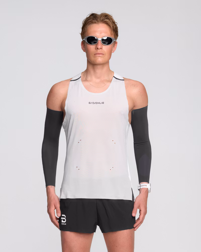 Male runner in a Dæhlie white running singlet with breathable, lightweight fabric and reflective logo for visibility.