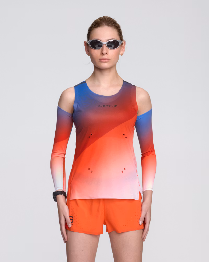 Female runner wearing the Dæhlie Elite Air running singlet with a vibrant red, white, and blue gradient.