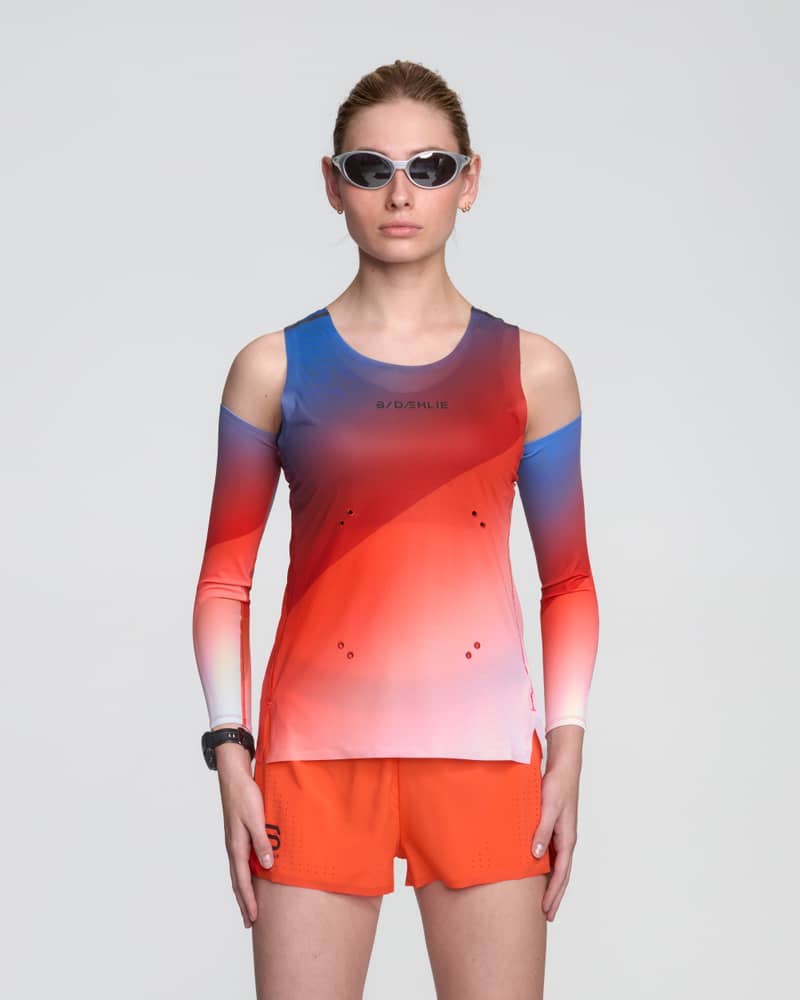 Female runner wearing the Dæhlie Elite Air running singlet with a vibrant red, white, and blue gradient.