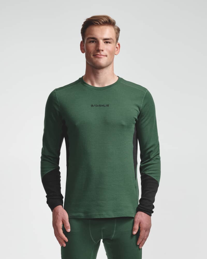 Dæhlie male model wearing green baselayer top with black sleeve panels, front view.