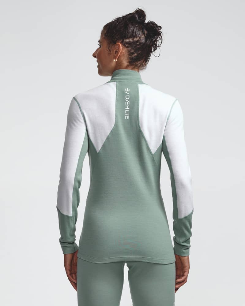 Dæhlie female model wearing sage green and white half-zip baselayer top, back view.
