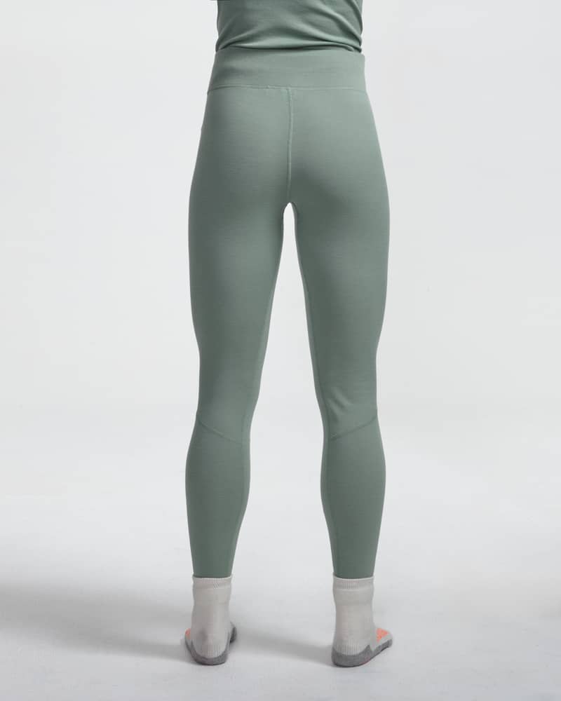 Dæhlie female model wearing light green baselayer leggings, back view close-up.