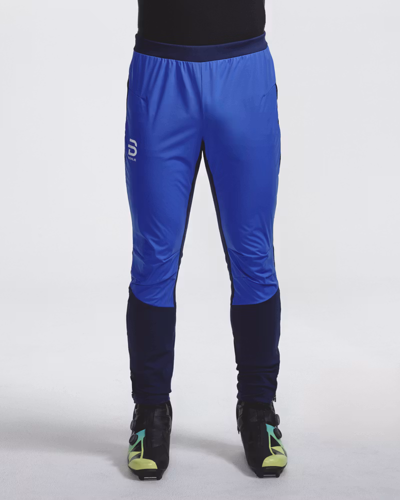 Front view of legs wearing blue and navy Dæhlie ski trousers with cross-country ski boots.