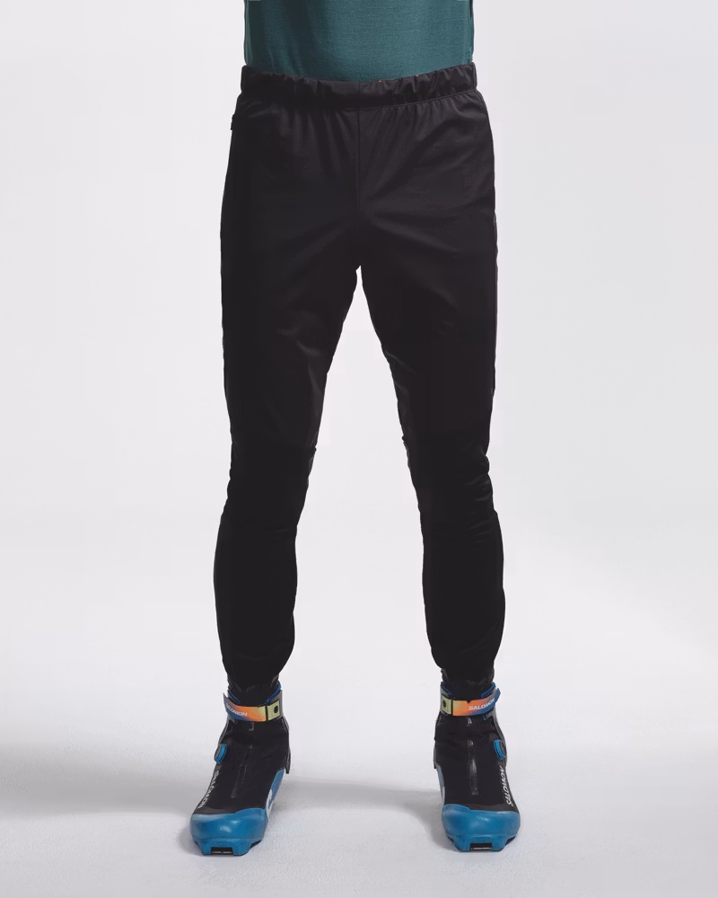 Front view of legs wearing black Dæhlie ski trousers with cross-country ski boots.