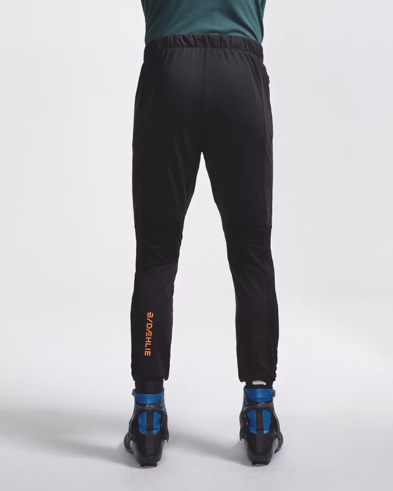 Rear view of legs wearing black Dæhlie ski trousers with cross-country ski boots.